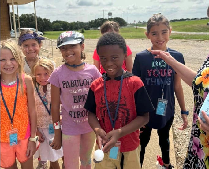 A bunch of kids grinning outside on a summer morning